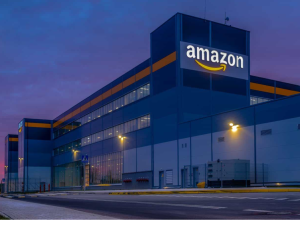  Amazon UK warehouse building at dusk with logo visible.