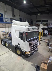  Heavy-duty Scania truck inside a warehouse workshop for maintenance or repair.